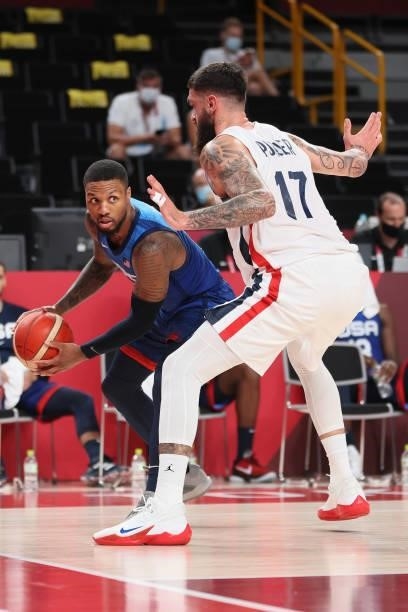 Damian Lillard of Team United States looks to pass the ball around Vincent Poirier of Team France during the second half of the Men's Preliminary...
