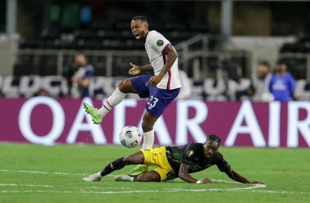 Kellyn Acosta of the United States leaps over Blair Turgott of Jamaica during a game between Jamaica and USMNT at AT&T Stadium on July 25, 2021 in...