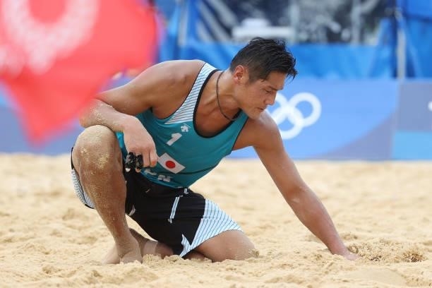 Yusuke Ishijima of Team Japan feels the sand against Team Italy during the Men's Preliminary - Pool F beach volleyball on day four of the Tokyo 2020...