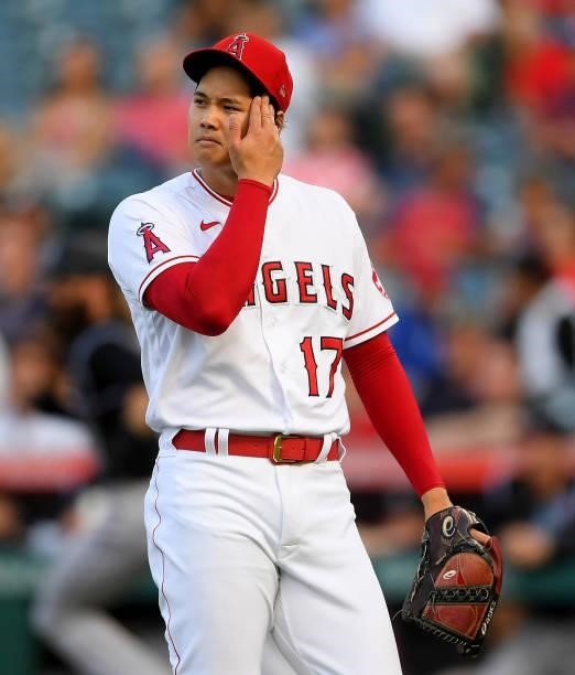 Shohei Ohtani of the Los Angeles Angels wipes his face after giving up a hit in the game against the Colorado Rockies at Angel Stadium of Anaheim on...