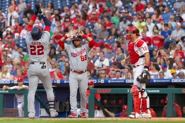 Juan Soto of the Washington Nationals celebrates with Gerardo Parra in front of J.T. Realmuto of the Philadelphia Phillies after hitting a three run...