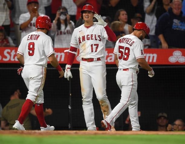 Adam Eaton and Jack Mayfield are congratulated by and Shohei Ohtani of the Los Angeles Angels after a home run in the game against the Colorado...