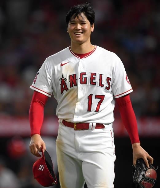 Shohei Ohtani of the Los Angeles Angels smiles at the umpires waiting to check his glove and hat after the sixth inning of the game against the...