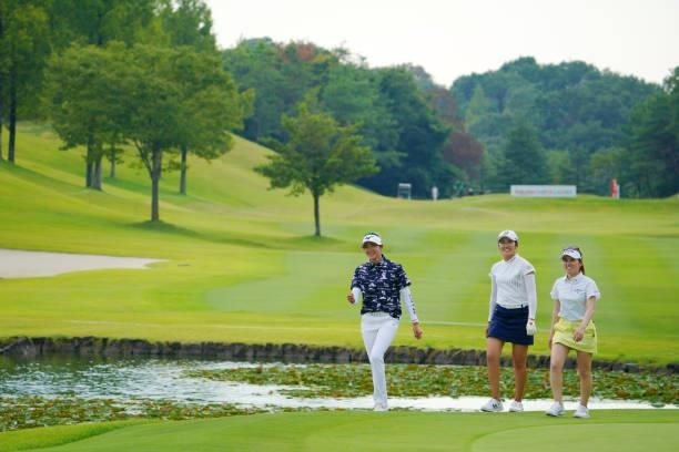 Mone Inami , Erika Hara and Yuna Nishimura of Japan share a laugh while returning to the club house as the play is suspended due to thunder clouds...