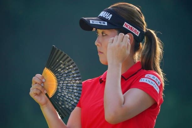 Mami Fukuda of Japan uses a traditional Japanese fan on the 17th tee during the first round of Rakuten Super Ladies at Tokyu Grand Oak Golf Club on...