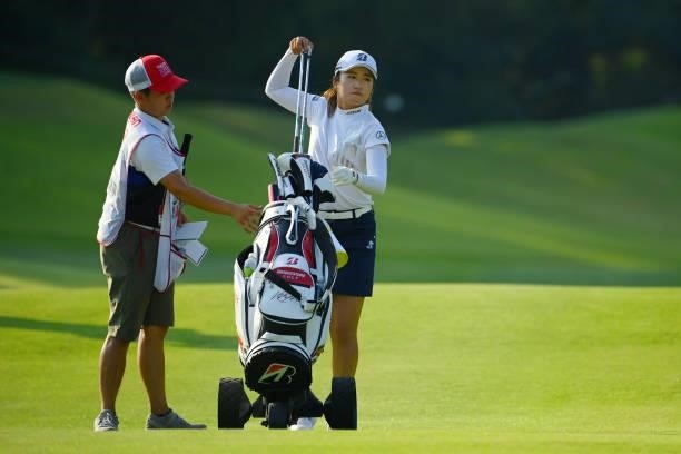 Mone Inami of Japan picks up irons before her second shot on the 14th hole during the first round of Rakuten Super Ladies at Tokyu Grand Oak Golf...