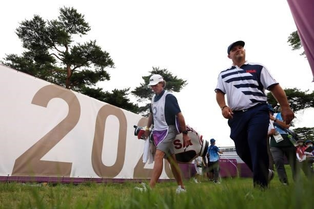 Patrick Reed of Team United States walks with his caddie and swing coach Kevin Kirk during the first round of the Men's Individual Stroke Play on day...