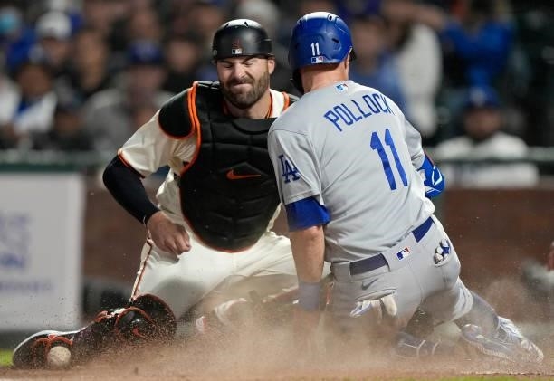 Pollock of the Los Angeles Dodgers scores from third base as Curt Casali of the San Francisco Giants can't hold onto the throw in the top of the...