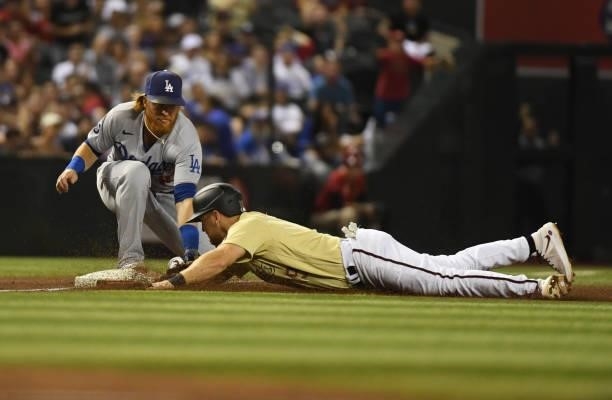 Josh VanMeter of the Arizona Diamondbacks slides safely into third base ahead of the tag by Justin Turner of the Los Angeles Dodgers during the...