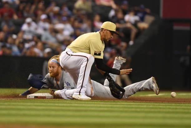Justin Turner of the Los Angeles Dodgers slides safely into third base as Nick Ahmed of the Arizona Diamondbacks waits for the throw from the...