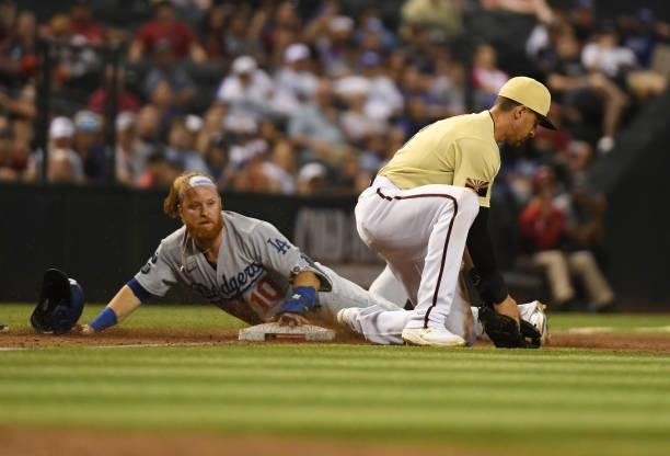 Justin Turner of the Los Angeles Dodgers slides safely into third base as Nick Ahmed of the Arizona Diamondbacks catches the throw from the outfield...