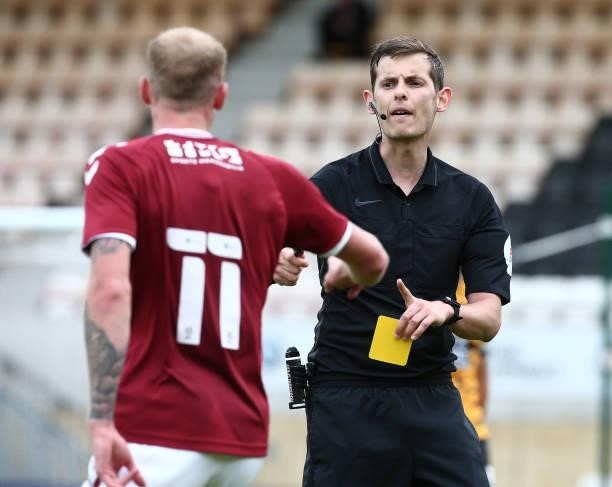 Referee Alan Dale shows a yellow card to Mitch Pinnock of Northampton Town during the Pre Season Friendly match between Cambridge United and...