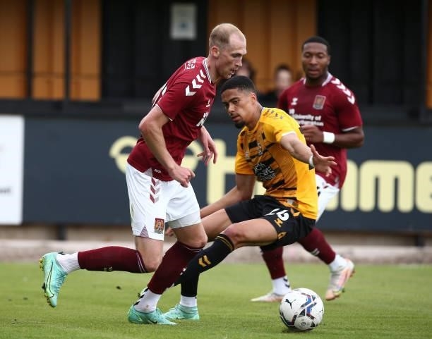 Mitch Pinnock of Northampton Town moves with the ball past Harvey Knibbs of Cambridge United during the Pre Season Friendly match between Cambridge...