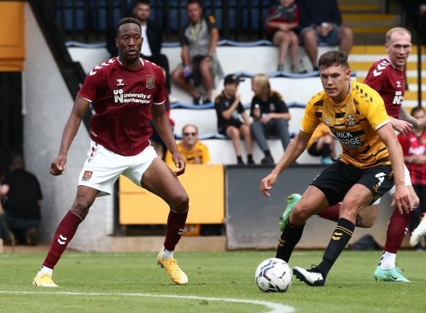 Nicke Kabamba of Northampton Town plays the ball watched by Paul Digby of Cambridge United during the Pre Season Friendly match between Cambridge...