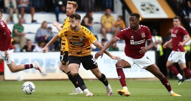 Jack Iredale of Cambridge United moves forward with the ball away from Nicke Kabamba of Northampton Town during the Pre Season Friendly match between...