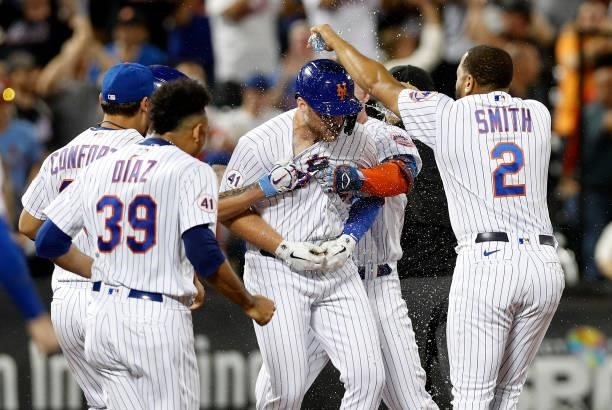 Brandon Drury of the New York Mets is mobbed by his teammates after his game winning hit against the Cincinnati Reds in the tenth inning at Citi...
