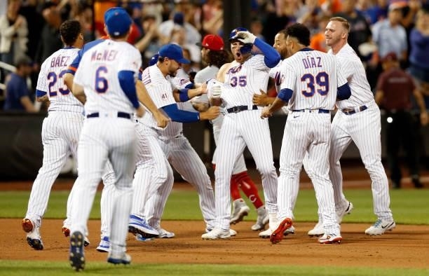 Brandon Drury of the New York Mets is mobbed by his teammates after his game winning hit against the Cincinnati Reds in the tenth inning at Citi...