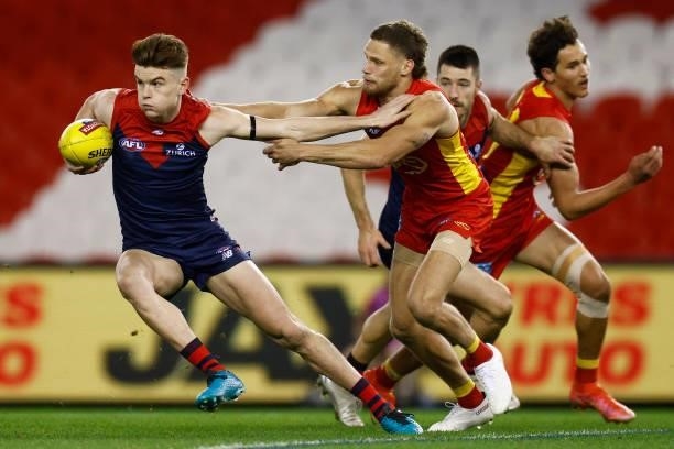 Bayley Fritsch of the Demons breaks a tackle attempt from Jy Farrar of the Suns during the round 20 AFL match between Gold Coast Suns and Melbourne...
