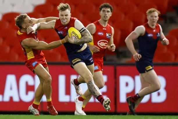 James Harmes of the Demons attempts to break a Darcy MacPherson of the Suns tackle during the round 20 AFL match between Gold Coast Suns and...