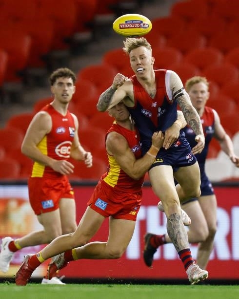 James Harmes of the Demons handballs whilst being tackled Darcy MacPherson of the Suns during the round 20 AFL match between Gold Coast Suns and...