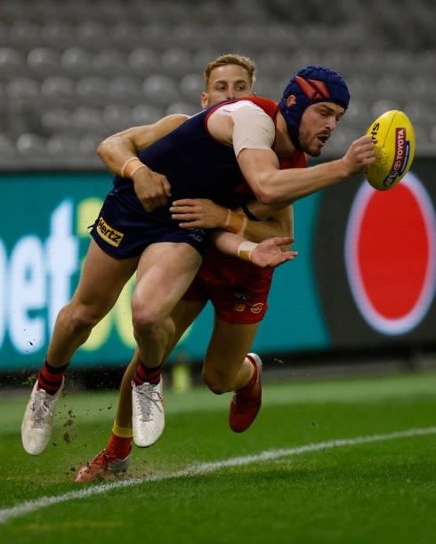 Angus Brayshaw of the Demons handballs whilst being tackled by Darcy MacPherson of the Suns during the round 20 AFL match between Gold Coast Suns and...