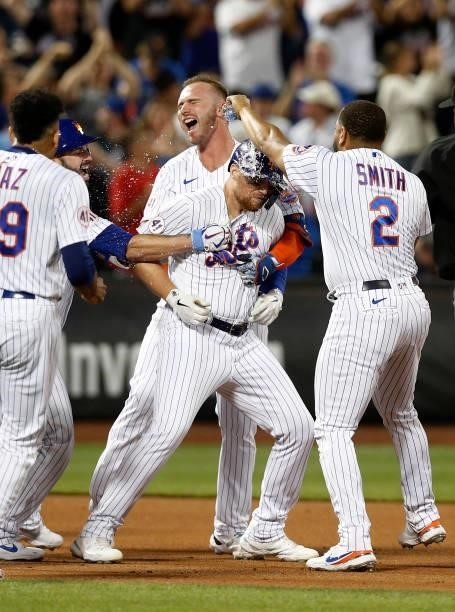 Brandon Drury of the New York Mets is mobbed by his teammates after his tenth inning game winning base hit against the Cincinnati Reds at Citi Field...