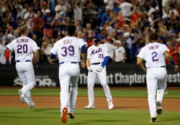 Brandon Drury of the New York Mets celebrates his tenth inning game winning base hit against the Cincinnati Reds with teammates Pete Alonso, Edwin...