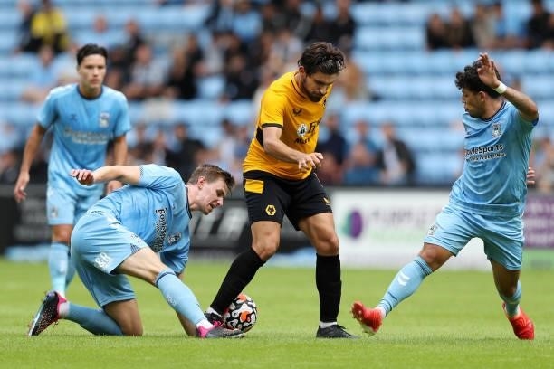 Ruben Neves of Wolverhampton Wanderers is challenged by Ben Sheaf and Gustavo Hamer of Coventry City during the Pre-Season friendly match between...