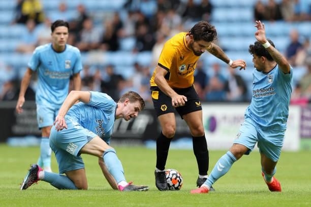 Ruben Neves of Wolverhampton Wanderers is challenged by Ben Sheaf and Gustavo Hamer of Coventry City during the Pre-Season friendly match between...