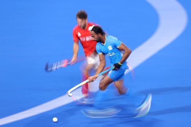 Hardik Singh of Team India runs with the ball whilst under pressure from Adam Graham Dixon of Team Great Britain during the Men's Quarterfinal match...