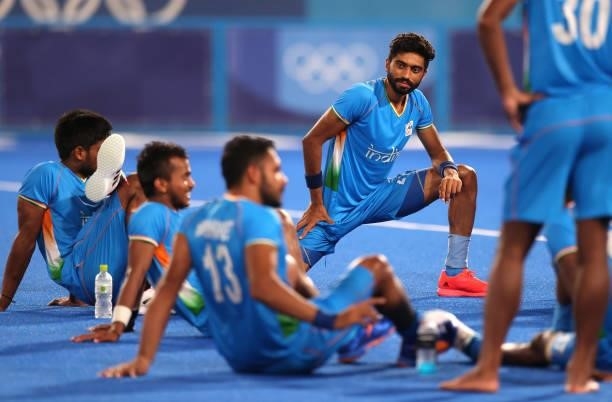 Shamsher Singh of Team India stretches alongside teammates following victory in the Men's Quarterfinal match between India and Great Britain on day...