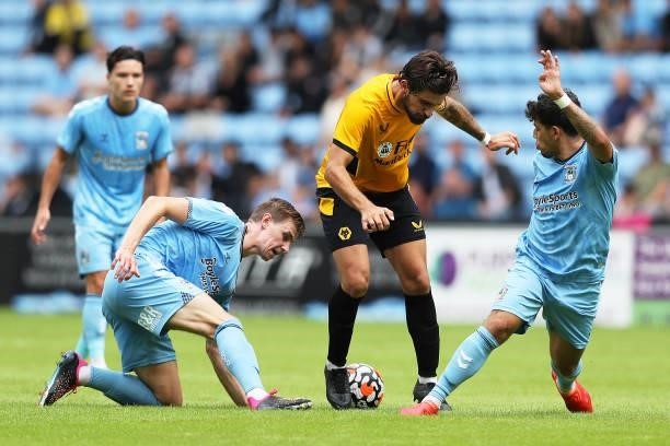 Ruben Neves of Wolverhampton Wanderers is challenged by Gustavo Hamer and Ben Sheaf of Coventry City during the Pre-Season Friendly between Coventry...