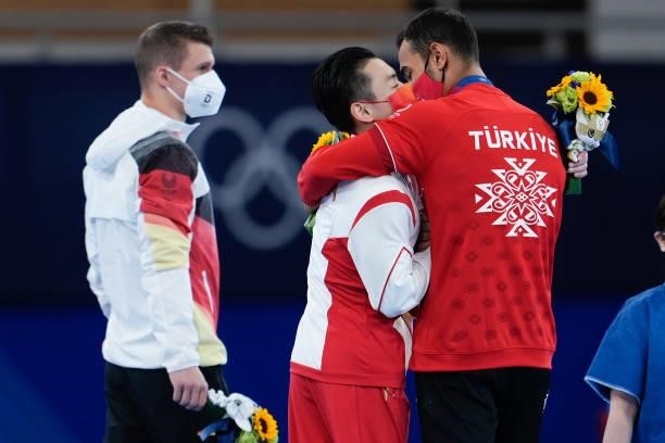 Silver medalist Lukas Dauser of Team Germany, gold medalist Zou Jingyuan of Team China and bronze medalist Ferhat Arican of Team Turkey celebrate...