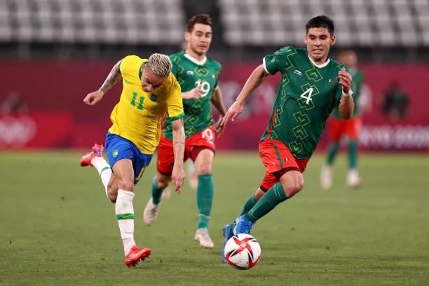 Antony of Team Brazil runs with the ball whilst under pressure from Jesus Angulo of Team Mexico during the Men's Football Semi-final match between...