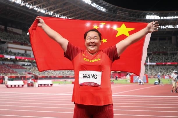 Wang Zheng of Team China celebrates with a Chinese national flag after winning second place in the Women's Hammer Throw Final on day eleven of the...
