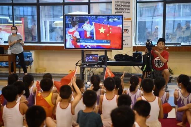 Students watch a television broadcasting gold medalist Zou Jingyuan of Team China during the Men's Parallel Bars Final on day eleven of the Tokyo...