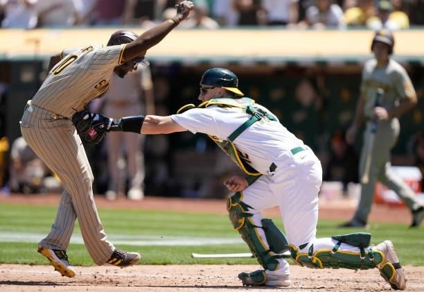 Jurickson Profar of the San Diego Padres gets tagged out at home plate by Sean Murphy of the Oakland Athletics in the top of the fourth inning at...