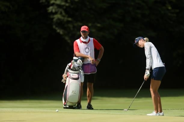Nelly Korda of Team United States chips to the 17th green as caddie Jason McDede looks on during the third round of the Women's Individual Stroke...