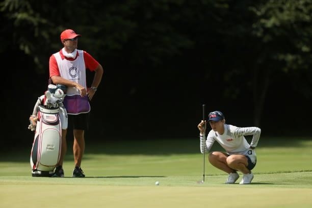 Nelly Korda of Team United States prepares to chip to the 17th green as caddie Jason McDede looks on during the third round of the Women's Individual...