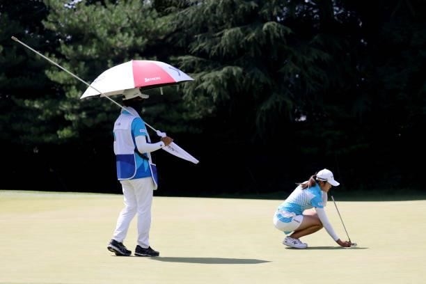 Mone Inami of Team Japan prepares to putt on the 17th green alongside caddie Tomoaki Okushima during the third round of the Women's Individual Stroke...