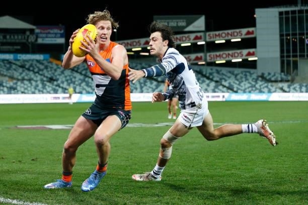 Lachie Whitfield of the Giants gathers the ball in front of Brad Close of the Cats during the round 21 AFL match between Geelong Cats and Greater...