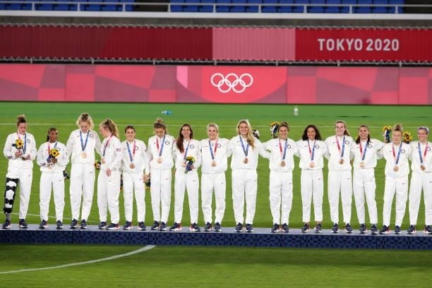 Bronze medalists Team USA celebrate on the podium with their bronze medals during the Women's Football Competition Medal Ceremony on day fourteen of...