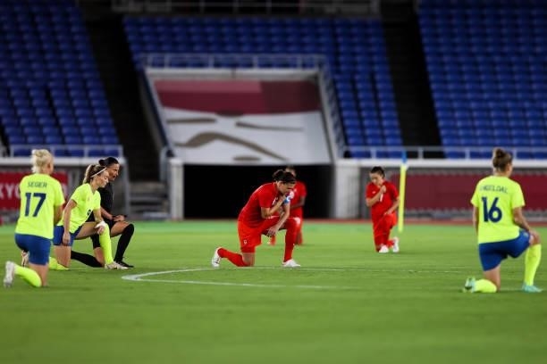Both team players kneel on the field during the Olympic women's football gold medal match between Sweden and Canada at International Stadium Yokohama...