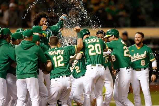Starling Marte of the Oakland Athletics celebrates with teammates at home plate after hitting a walk-off three-run home run in the bottom of the...