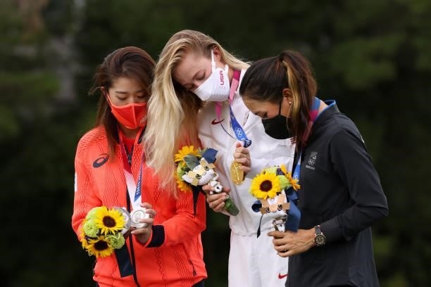 Silver medalist Mone Inami of Team Japan, gold medalist Nelly Korda of Team United States and bronze medalist Lydia Ko of Team New Zealand look at...