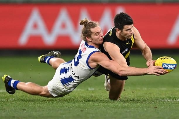 Trent Cotchin of the Tigers handballs whilst being tackled by Jed Anderson of the Kangaroos during the round 21 AFL match between Richmond Tigers and...