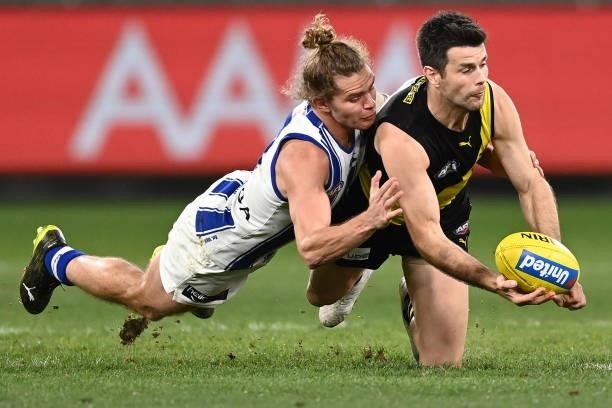 Trent Cotchin of the Tigers handballs whilst being tackled by Jed Anderson of the Kangaroos during the round 21 AFL match between Richmond Tigers and...