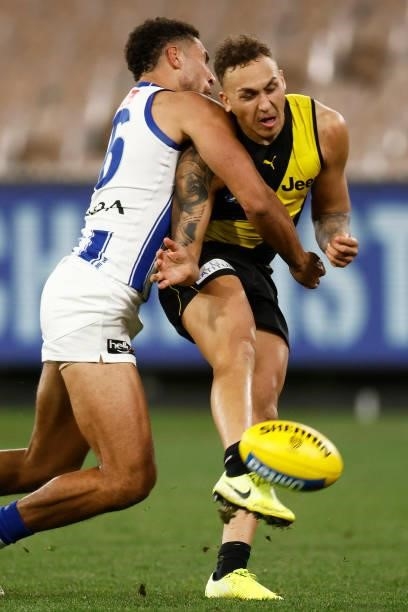 Shai Bolton of the Tigers kicks for goal under pressure from Aiden Bonar of the Kangaroos during the round 21 AFL match between Richmond Tigers and...
