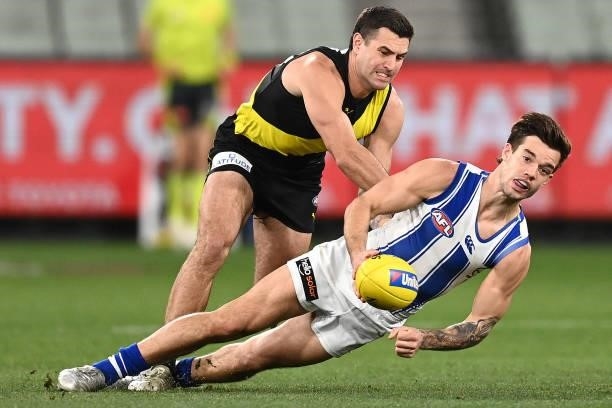 Jy Simpkin of the Kangaroos handballs whilst being tackled by Jack Graham of the Tigers during the round 21 AFL match between Richmond Tigers and...