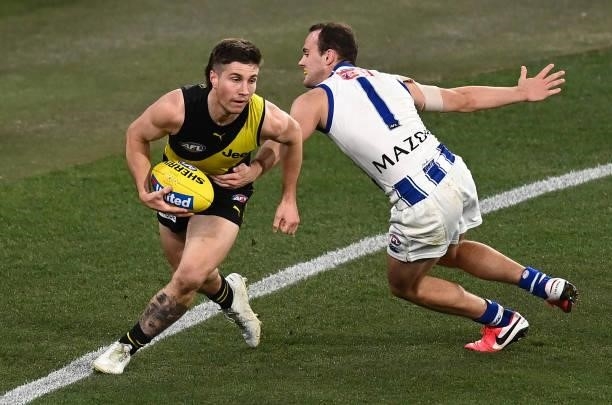 Liam Baker of the Tigers is tackled by Jack Mahony of the Kangaroos during the round 21 AFL match between Richmond Tigers and North Melbourne...